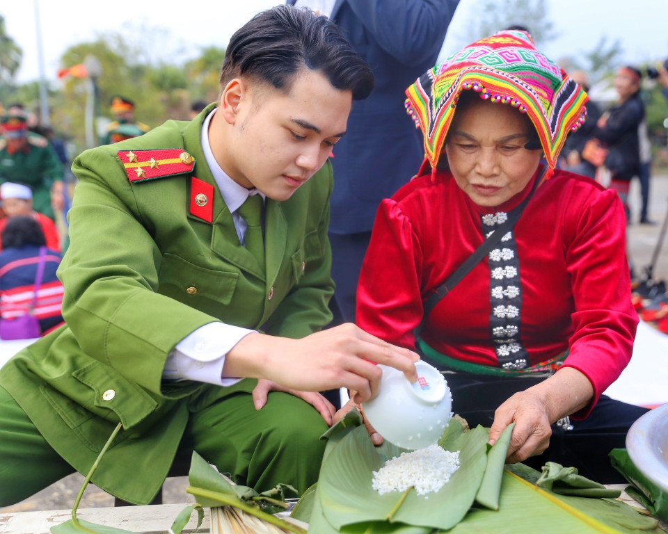 Đồng bào dân tộc Thái cùng chiến sỹ công an tham gia gói bánh chưng xanh. (Ảnh: Tuấn Đức/TTXVN)