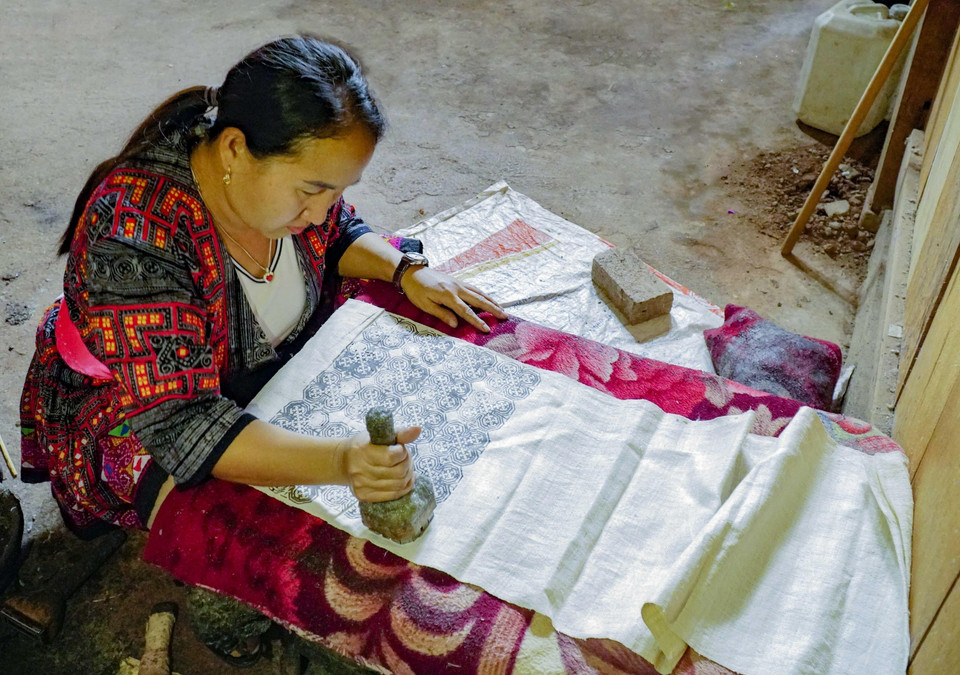 Phụ nữ Mông dùng sáp ong để tạo hoa văn lên vải. (Ảnh: Xuân Tư/TTXVN)