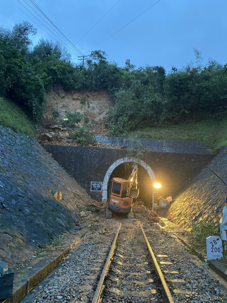 Một máy cẩu nhỏ được huy động để múc đất lấp ngay cửa hầm. (Ảnh: CTV/Vietnam+)