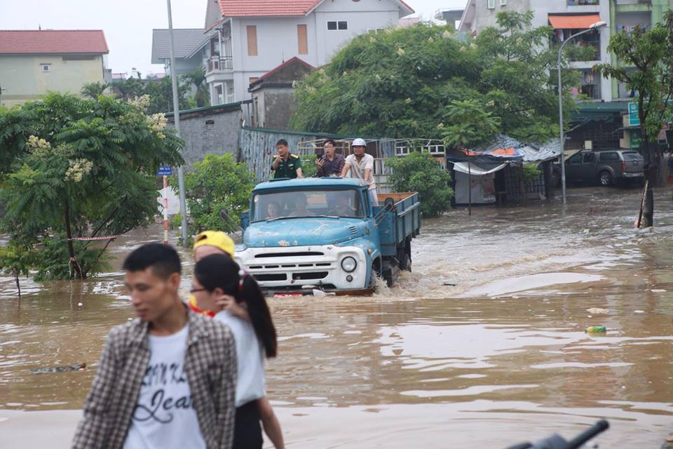 Người dân Khu đô thị Resco (Cổ Nhuế) nhờ xe tải vượt qua vùng nước ngập. (Ảnh: Lê Minh Sơn/Vietnam+)