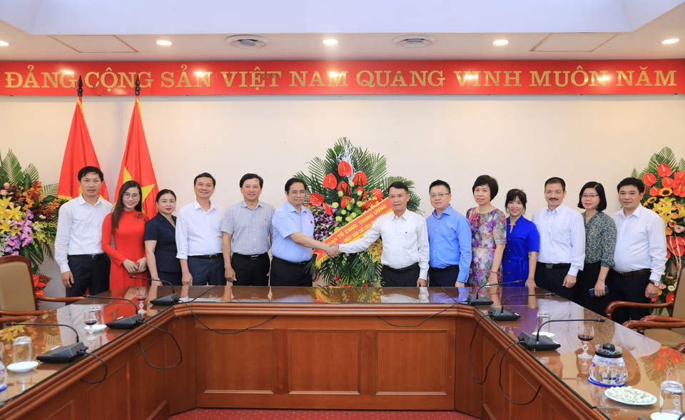 Trưởng Ban Tổ chức Trung ương Phạm Minh Chính tặng hoa chúc mừng TTXVN. (Ảnh: Thành Đạt/TTXVN)