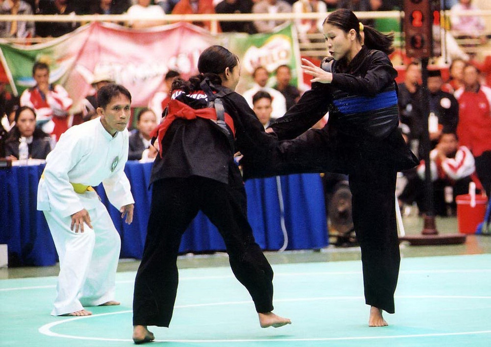 7 năm khoác áo đội tuyển Pencak Silat quốc gia, vận động viên Trịnh Thị Mùi (bên phải) đã giành được 7 Huy chương vàng toàn quốc, 4 Huy chương vàng SEA Games, 2 Huy chương vàng châu Á, 3 Huy chương vàng thế giới hạng 60kg. 4 lần liên tiếp được bầu chọn là vận động viên tiêu biểu (1999-2003); 3 lần được tặng thưởng Huân chương Lao động hạng Nhì, Ba. Cô được mệnh danh là 'cô gái vàng', võ sỹ bất bại của Pencak Silat Việt Nam một thời khuynh đảo ở nhiều sàn đấu khi liên tiếp giành Huy chương vàng từ SEA Games đến giải vô địch châu Á và giải vô địch thế giới. (Ảnh: Quang Hải/TTXVN)