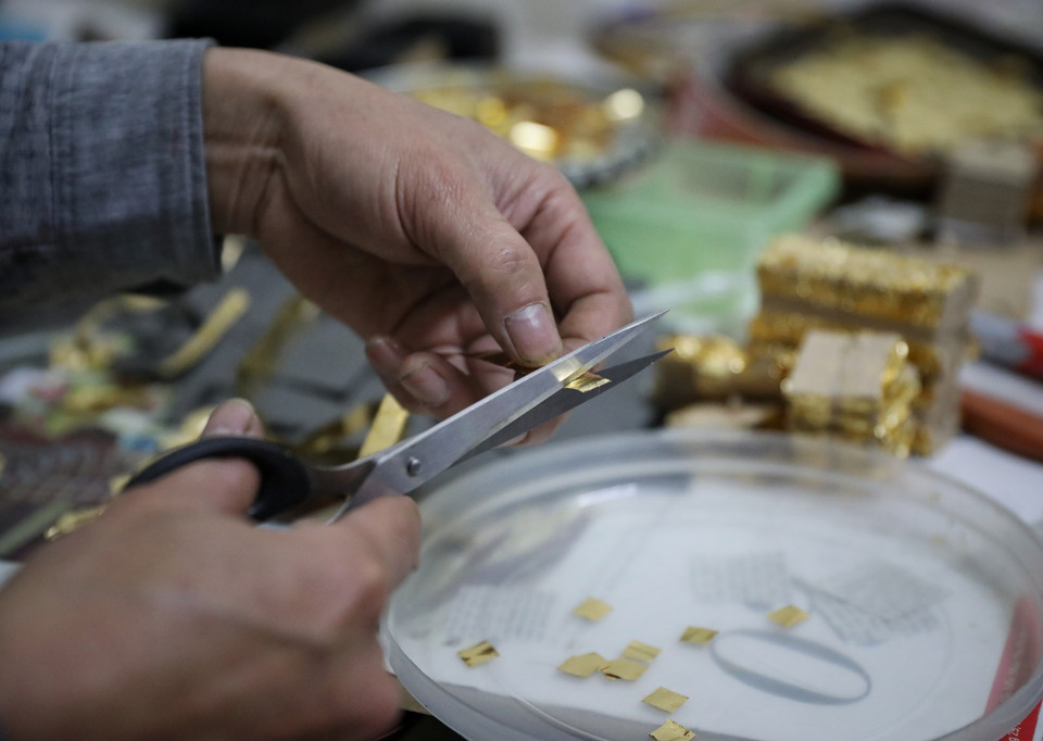  Công đoạn cắt điệp-vàng được cán mỏng và cắt thành từng miếng có diện tích 1cm2 để chuẩn bị đập vỡ. (Ảnh: Danh Lam/TTXVN)