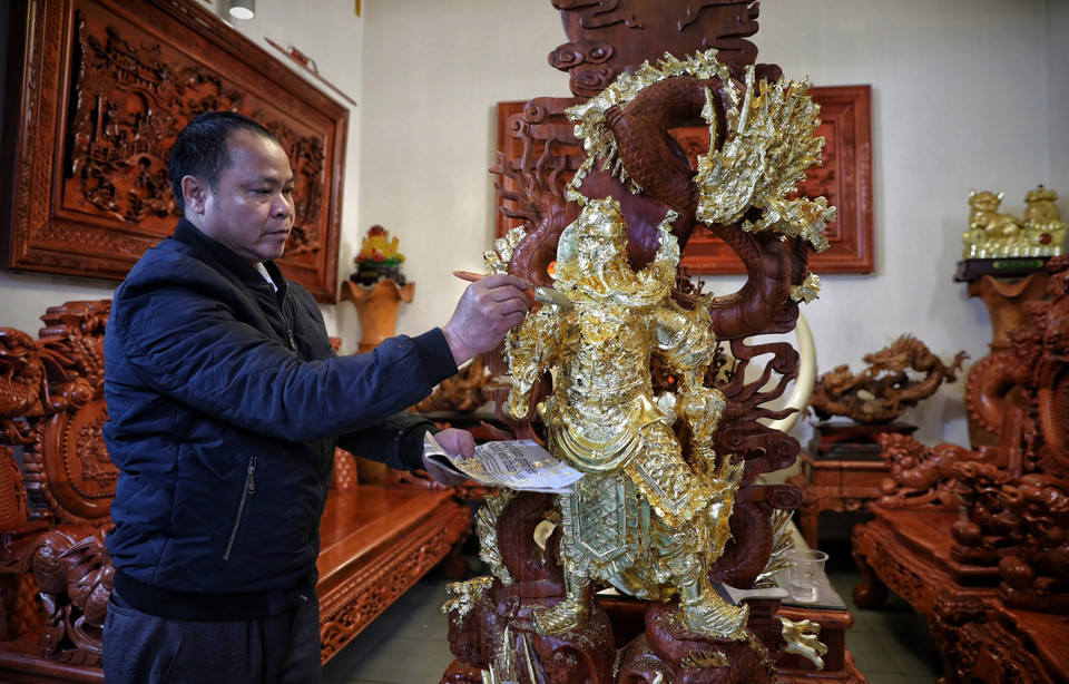 Nghệ nhân Nguyễn Anh Chung thếp vàng lên tượng cho khách hàng. (Ảnh: Danh Lam/TTXVN)