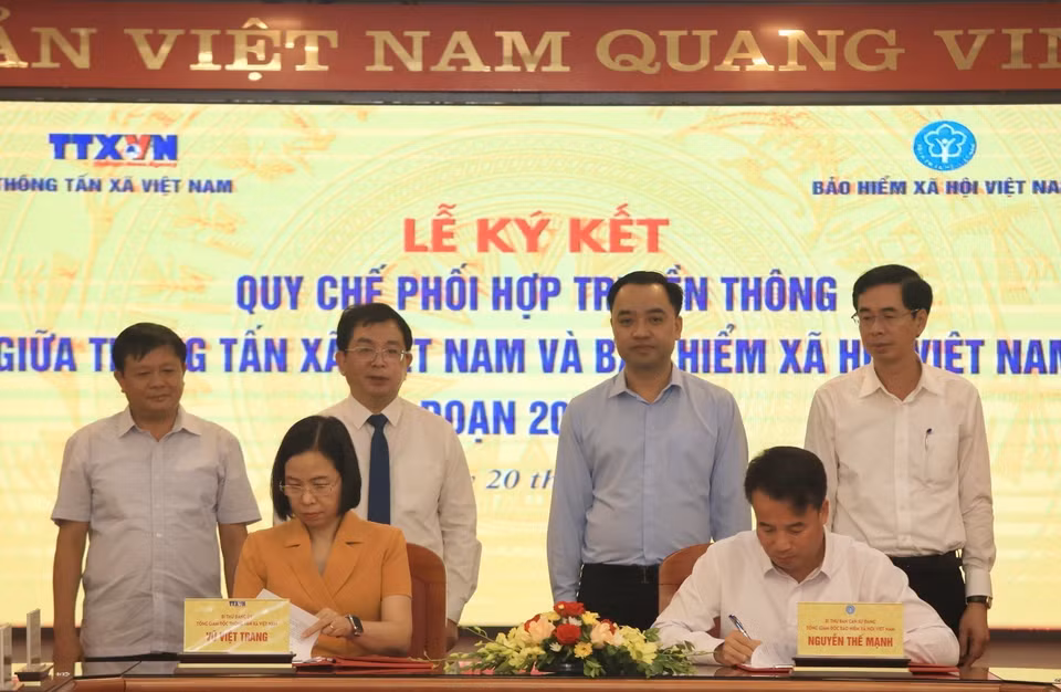 Tổng Giám đốc Thông tấn xã Việt Nam Vũ Việt Trang và Tổng Giám đốc Bảo hiểm xã hội Việt Nam Nguyễn Thế Mạnh trao đổi biên bản ký kết hợp tác tại buổi lễ. (Ảnh: Tuấn Anh/TTXVN)
