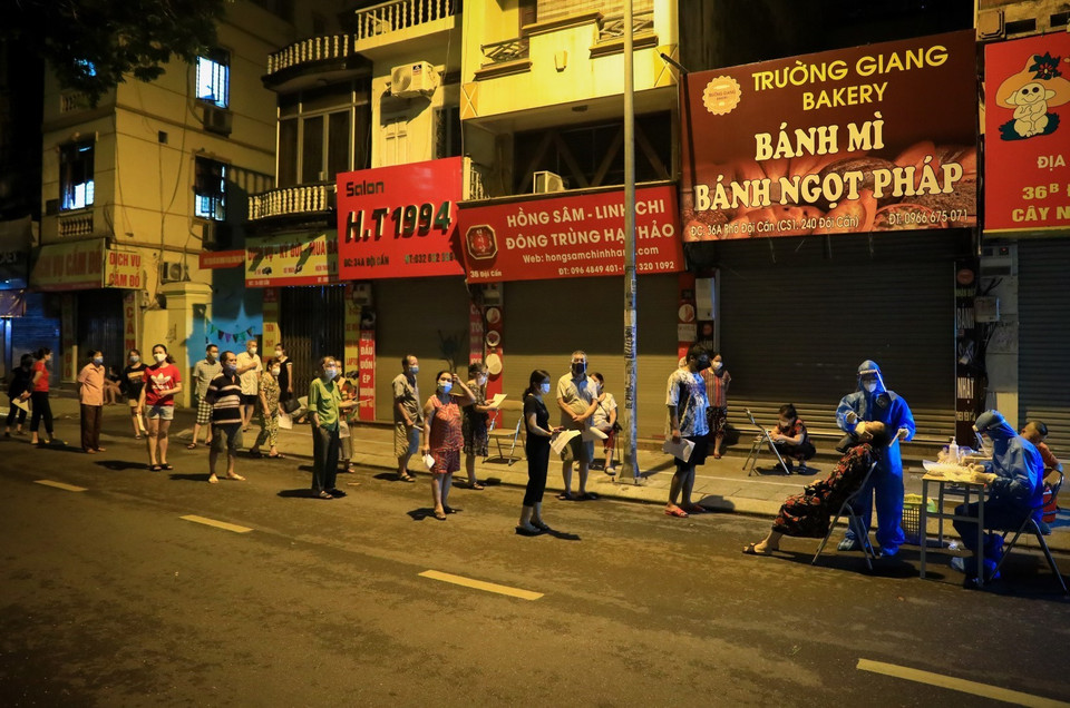 Người dân xếp hàng đảm bảo giãn khoảng cách chờ lấy mẫu xét nghiệm ngay trên mặt đường Đội Cấn. (Ảnh: Thành Đạt/TTXVN)