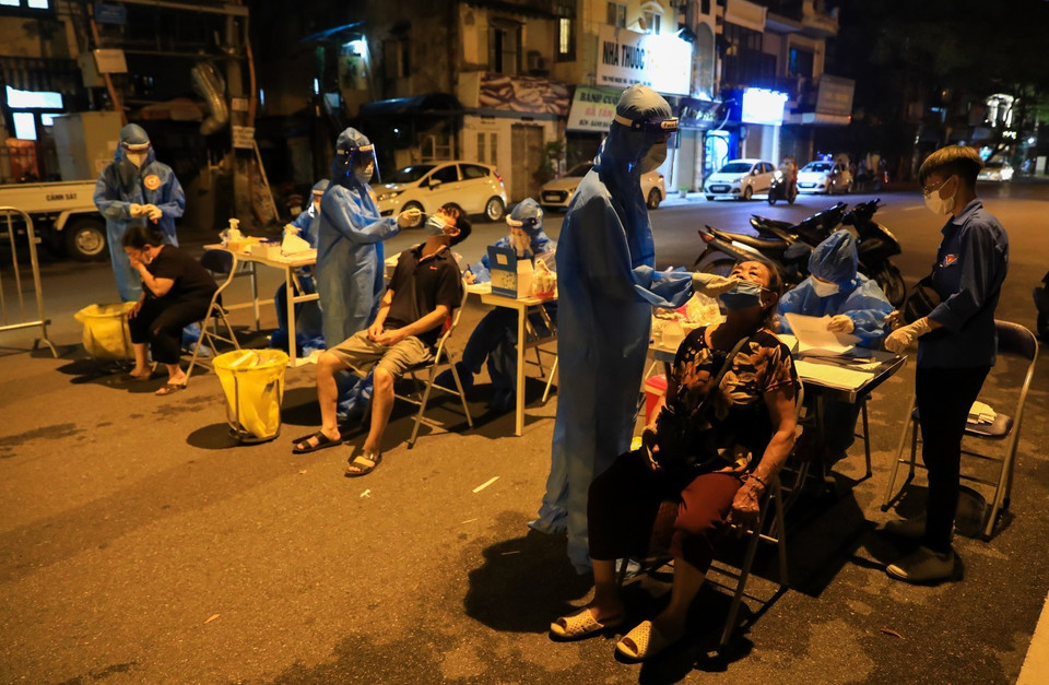 Lực lượng Y tế phường Đội Cấn lấy mẫu xét nghiệm xuyên đêm cho người dân ngay trên mặt đường phố Ngọc Hà. (Ảnh: Thành Đạt/TTXVN)