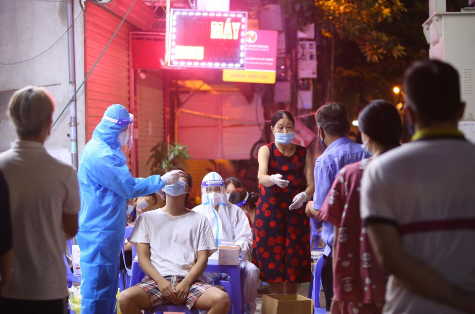 Nhân viên y tế lấy mẫu xét nghiệm cho người dân phường Vĩnh Tuy (quận Hai Bà Trưng) tại điểm lấy mẫu 461 phố Minh Khai. (Ảnh: Hoàng Hiếu/TTXVN)