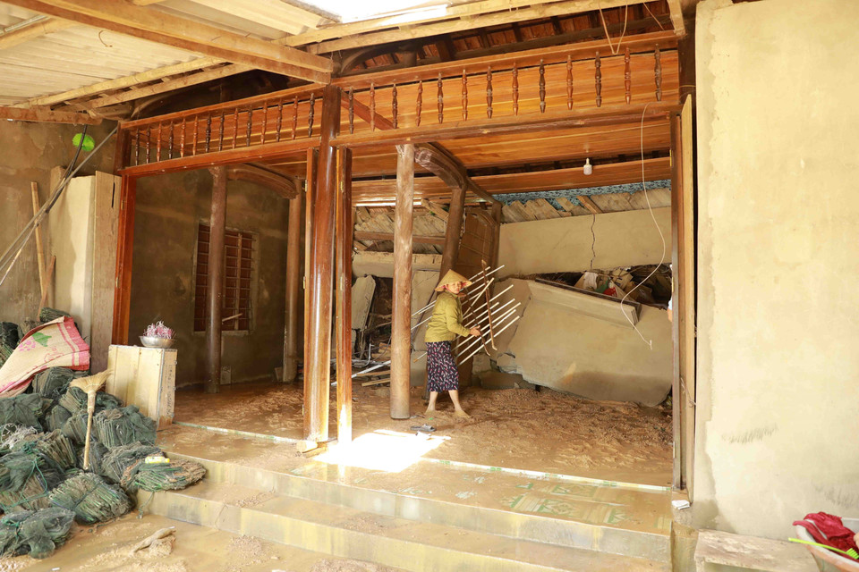 Chị Nguyễn Thị Lan dọn dẹp đồ dùng để rời khỏi ngôi nhà bị sạt lở đất làm hư hòng, gây mất an toàn. (Ảnh: Vũ Sinh/TTXVN)