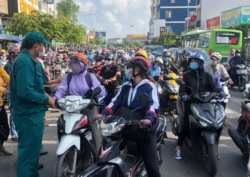 Lực lượng chức năng hướng dẫn người dân khai báo y tế tại chốt kiểm soát giao lộ Phan Văn Trị-Phạm Văn Đồng. (Ảnh: TTXVN phát)