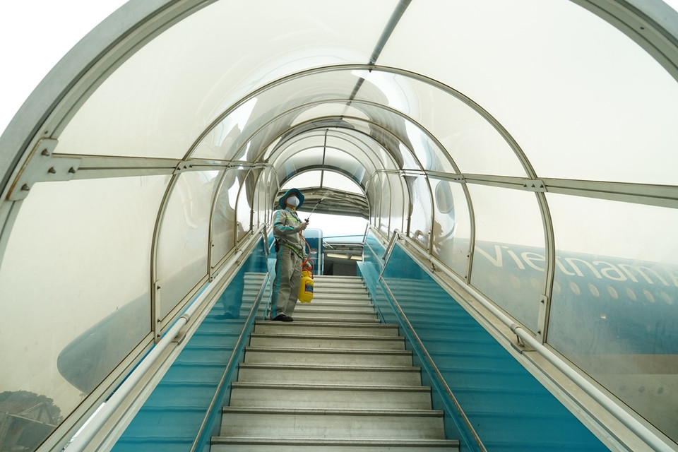 Khử trùng lan can, mui che ống lồng xe thang - vị trí hàng trăm khách tiếp xúc trên chuyến bay mỗi ngày. (Ảnh: CTV/Vietnam+)