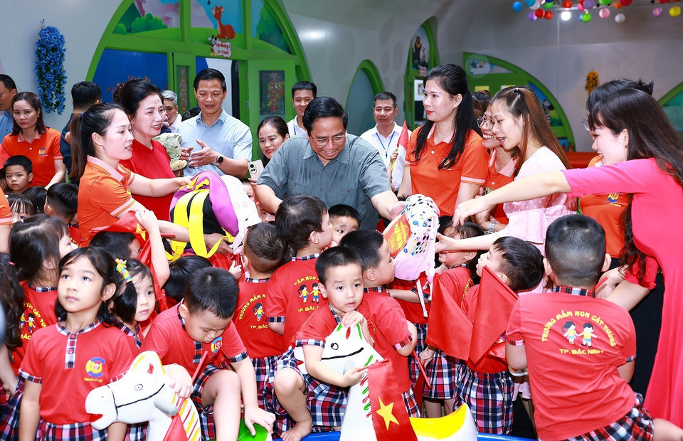 Thủ tướng Phạm Minh Chính tặng quà học sinh trường mầm non Cát Tường trong khu nhà ở xã hội tại thành phố Bắc Ninh. (Ảnh: Dương Giang/TTXVN)