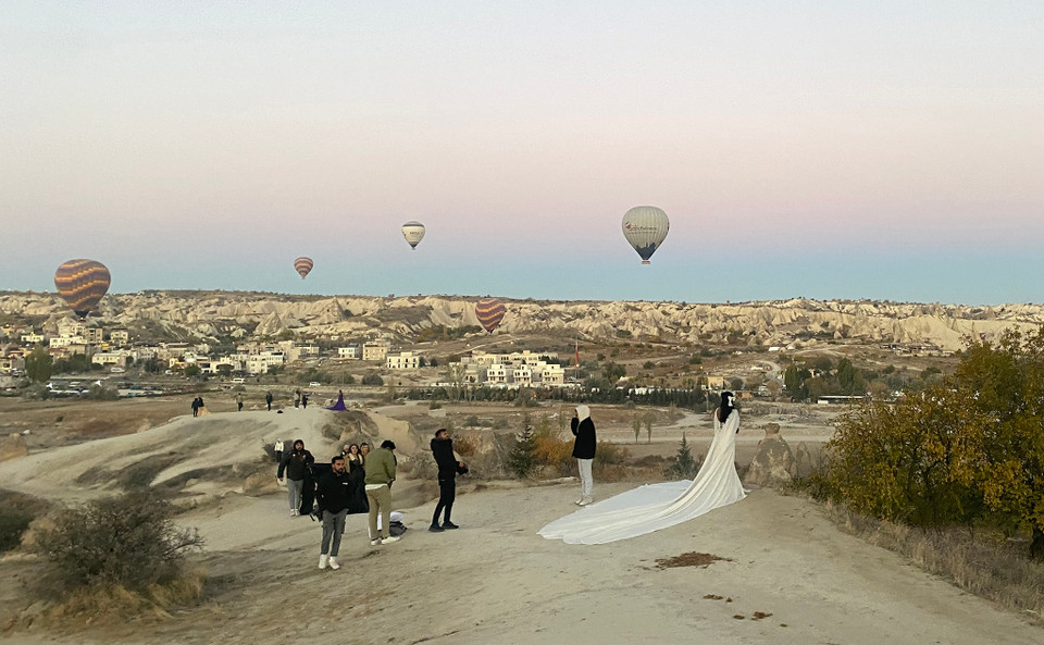 Dưới chân chúng tôi, có rất nhiều người tới để chụp những bức hình cưới, lưu niệm với những dãy núi hình thù đẹp mắt và đặc biệt trên đầu, phía sau và thậm chí dưới chân họ là những chiếc khinh khí cầu bay lơ lửng, tạo nên một bức tranh tuyệt mỹ. (Ảnh: Yên Thủy/Vietnam+)