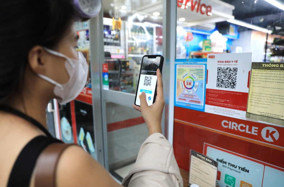 Khách hàng đến siêu thị phải quét mã QR và xịt khử khuẩn trước khi vào mua hàng. (Ảnh: Thành Đạt/TTXVN)