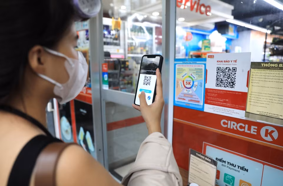 Khách hàng đến siêu thị phải quét mã QR và xịt khử khuẩn trước khi vào mua hàng. (Ảnh: Thành Đạt/TTXVN)