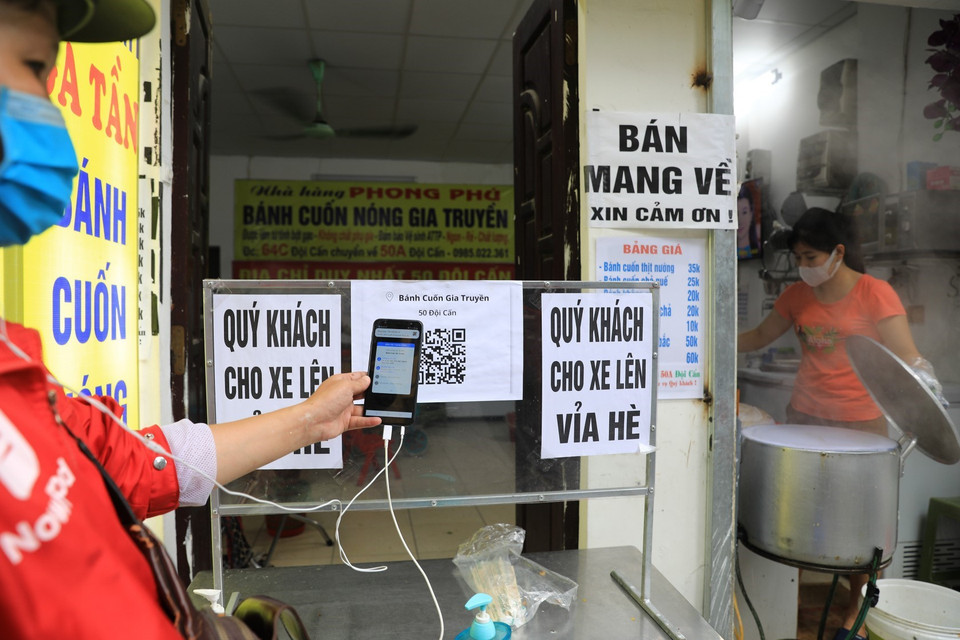 Tại một cửa hàng bán bánh cuốn trên phố Đội Cấn, các shipper đến lấy hàng phải quét mã QR-code để khai báo y tế rồi mới được lấy hàng. (Ảnh: Thành Đạt/TTXVN)