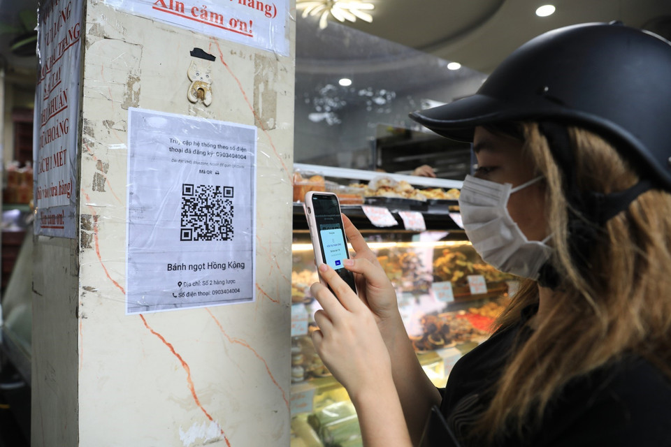 Khách sẽ được các chủ cửa hàng yêu cầu quét mã QR trước khi mua hàng. (Ảnh: Thành Đạt/TTXVN)