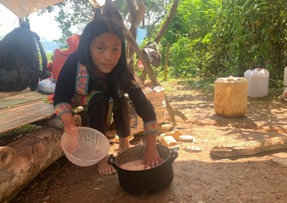 Một bé gái nấu cơm trưa, chờ mọi người đi làm vàng về. (Ảnh: Nhóm PV TTXVN tại Lai Châu)