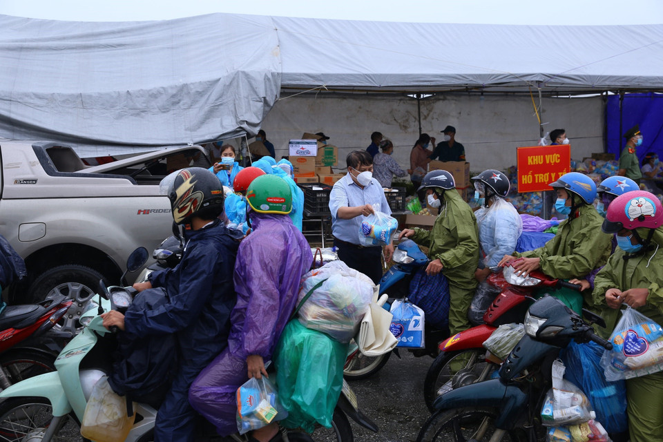 Người dân được nhận quà tặng của các nhà hảo tâm trước khi rời điểm trung chuyển Khu công nghiệp hỗ trợ Nam Hà Nội để tiếp tục hành trình về quê, chiều 9/10. (Ảnh: Hoàng Hiếu/TTXVN)