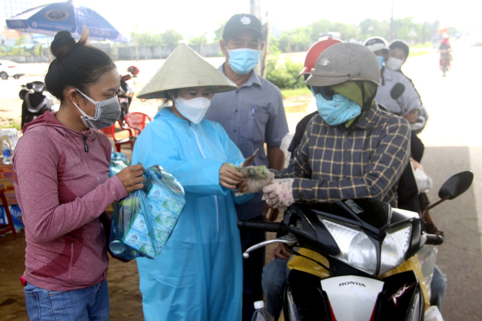 Các thành viên thực hiện Chương trình trao tiền và quà hỗ trợ cho người từ miền Nam về quê tránh dịch. (Ảnh: Phước Tuệ/TTXVN)