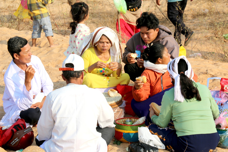Sau nghi thức cúng trong Lễ tảo mộ, từng gia đình dòng tộc đồng bào Chăm ngồi quây quần bên nhau chia sẻ và cùng ăn đồ cúng mang theo. (Ảnh: Nguyễn Thanh/TTXVN)