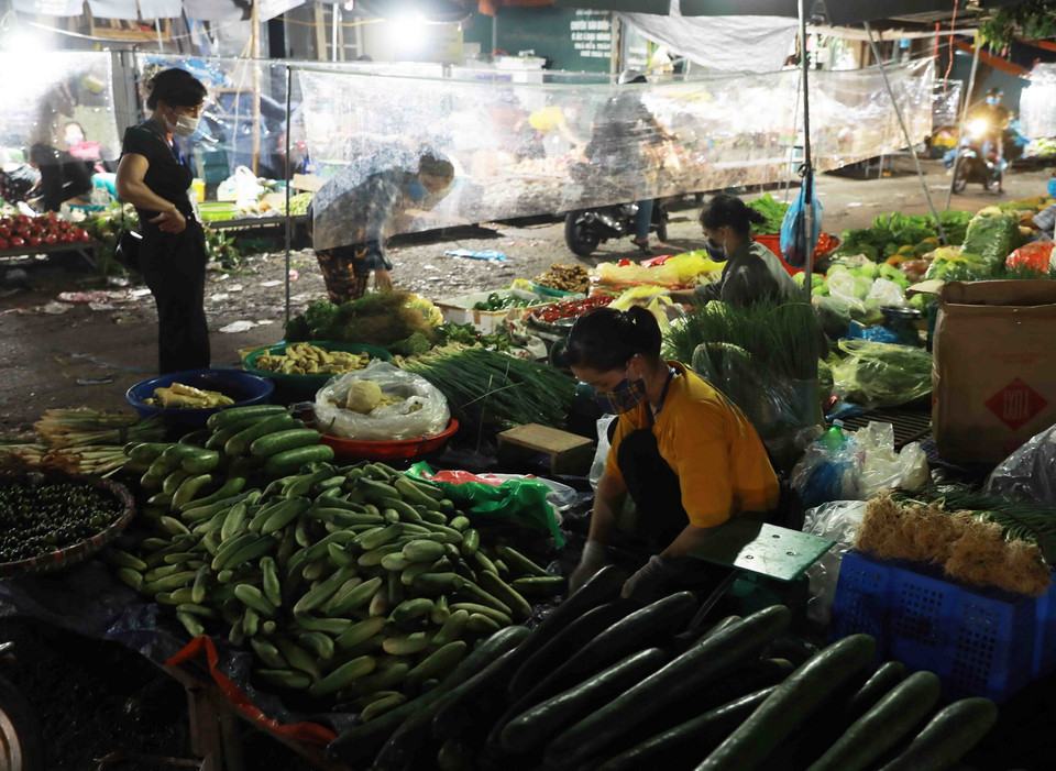 Các hoạt động mua, bán tại chợ đầu mối Nam Hà Nội, quận Hoàng Mai đều phải đảm bảo giữ khoảng cách an toàn và có tấm kính chắn giữa người bán, người mua. (Ảnh: Vũ Sinh/TTXVN)