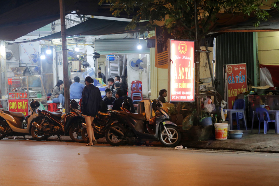 Một quán ăn ở phố Thanh Nhàn, quận Hai Bà Trưng chiếm toàn bộ vỉa hè để kinh doanh, buộc người đi bộ phải đi dưới lòng đường (chụp tối 23/3/2021). (Ảnh: Hoàng Hiếu/TTXVN)