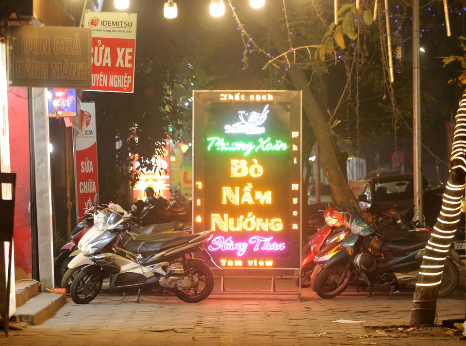 Quán ăn Phương Xoăn trên phố Võ Thị Sáu, quận Hai Bà Trưng chiếm dụng toàn bộ vỉa hè thành nơi để xe và biển quảng cáo, biến lối đi thành ngõ cụt, người đi bộ chỉ còn cách xuống lòng đường để đi (ảnh chụp tối 23/3/2021). (Ảnh: Hoàng Hiếu/TTXVN)