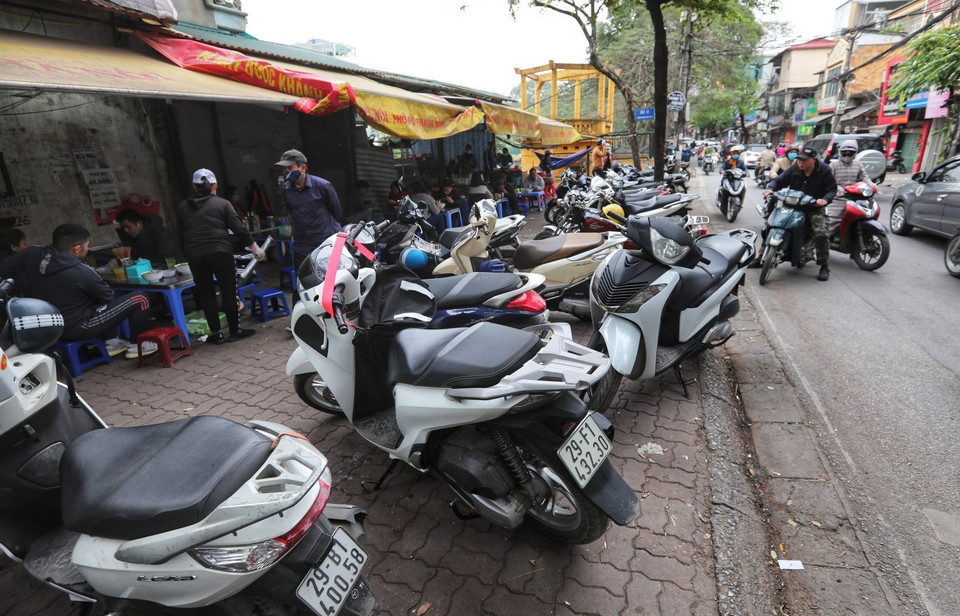 Một cửa hàng ăn sáng trên phố Hoàng Hoa Thám (quận Ba Đình) chiếm gần hết vỉa hè để bán hàng và cho khách để xe máy. (Ảnh: Thành Đạt/TTXVN)