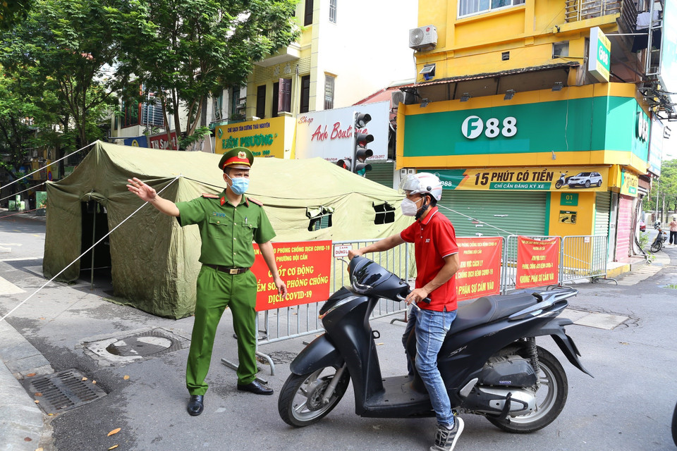 Lực lượng công an hướng dẫn người dân không vào khu vực bị phong tỏa. (Ảnh: Hoàng Hiếu/TTXVN)
