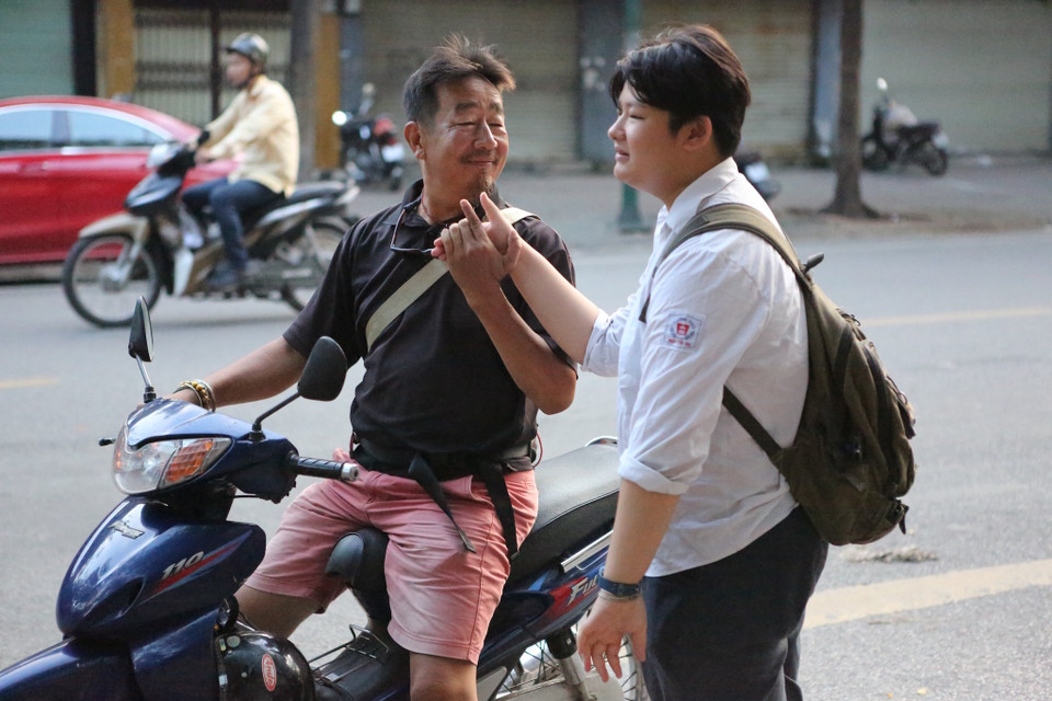 Ông bố nắm chặt tay dặn dò con trước khi vào phòng thi. (Ảnh: Minh Sơn/Vietnam+)