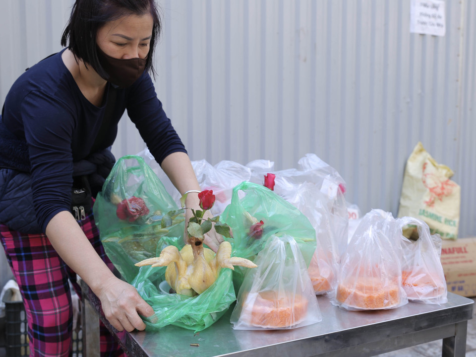 Gà luộc sẵn, buộc cánh tiên, ngậm hoa để cúng là một trong những mặt hàng bán chạy nhất sáng 30 Tết tại chợ Hàng Bè. (Ảnh: Hoàng Hiếu/TTXVN)