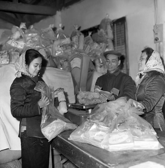  Công ty Bách hóa Bán lẻ Hà Nội tổ chức đóng gói hàng Tết đúng tiêu chuẩn định lượng và điều vận tốt hàng hóa đến bán tại các cửa hàng bách hóa và các quầy hàng tập thể ở cơ quan, xí nghiệp, phục vụ nhân dân trong dịp Tết Canh Tuất 1970. (Ảnh: Trần Phác/TTXVN)