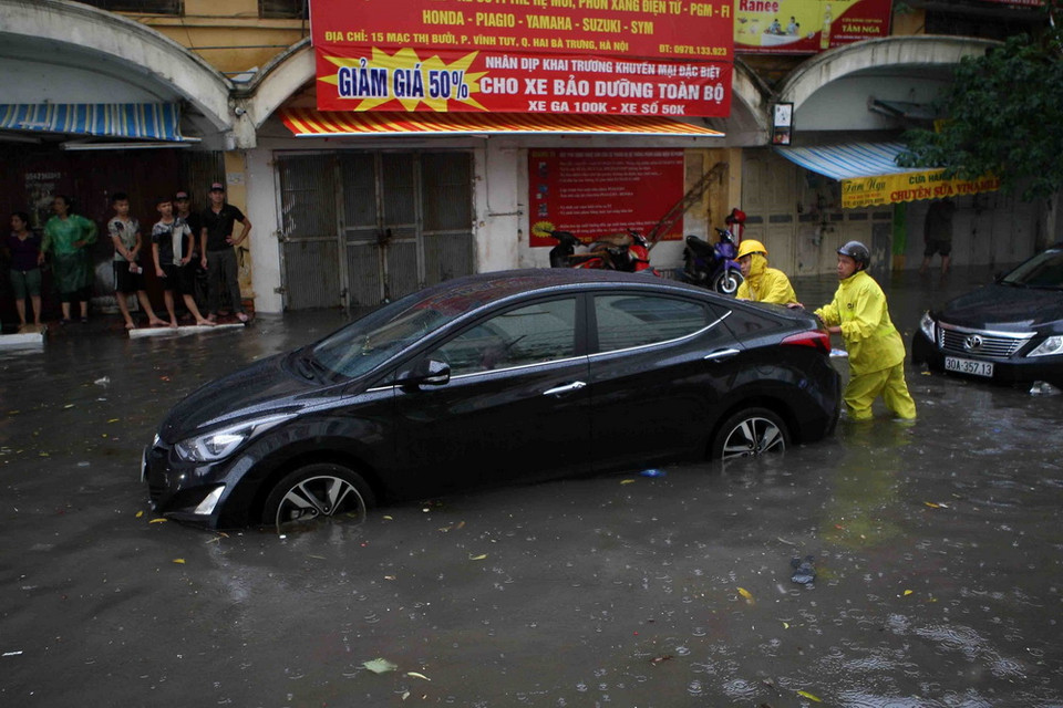 Hỗ trợ đẩy ôtô của người dân ra khỏi vùng ngập trên phố Mạc Thị Bưởi. (Ảnh: Thanh Tùng/TTXVN)
