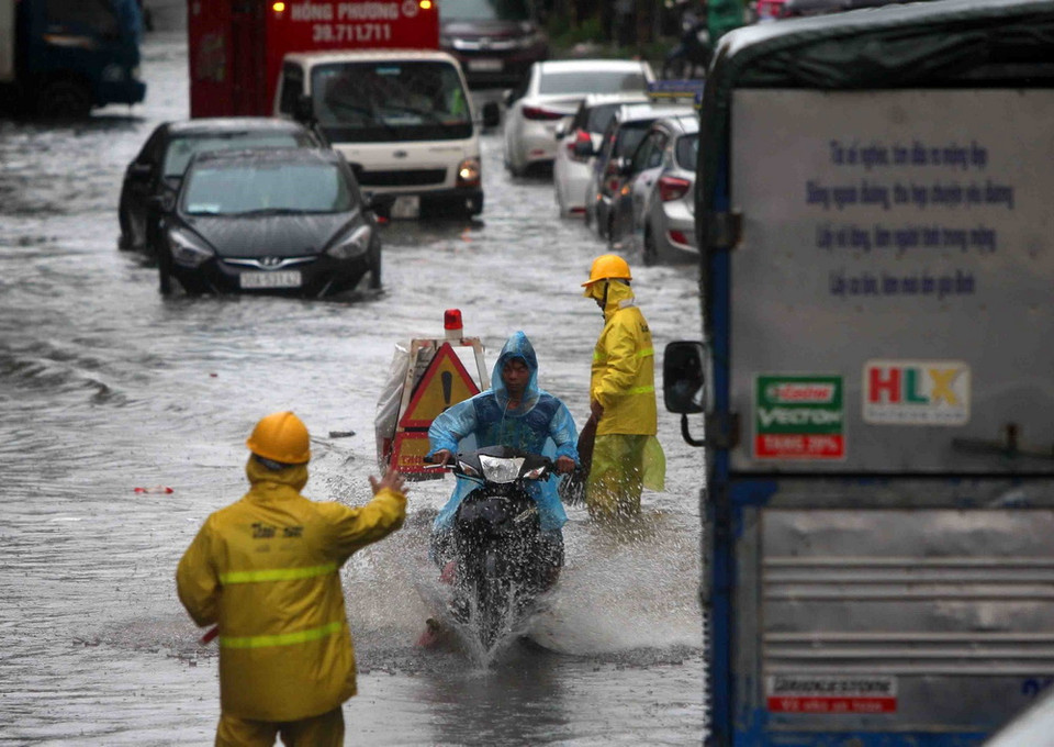 Công nhân Xí nghiệp thoát nước Hà Nội túc trực, cảnh báo người đi đường tại các điểm ngập nguy hiểm. (Ảnh: Thanh Tùng/TTXVN)