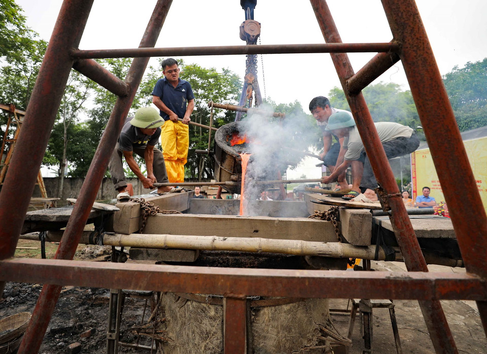 Các nghệ nhân thực hiện rót đồng vào khuôn trống. (Ảnh: Thanh Tùng/TTXVN)