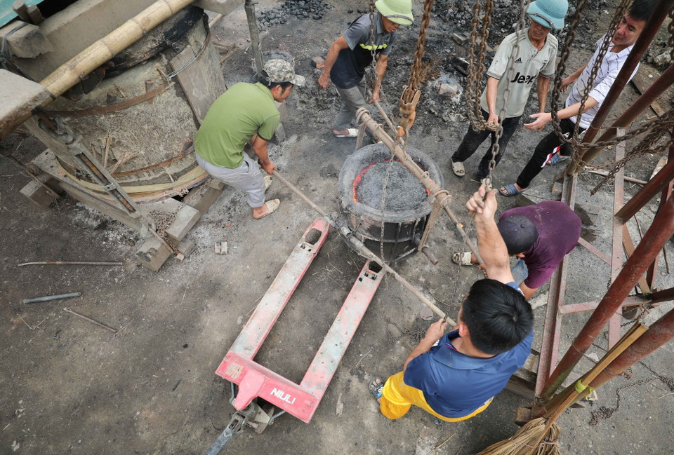 Đồng đã nấu chảy được kéo lên cao để rót vào khuôn. (Ảnh: Thanh Tùng/TTXVN)