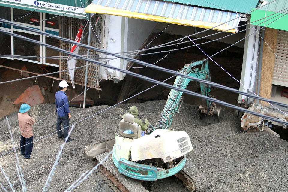 Lực lượng chức năng đang thực hiện việc san lấp 'hố tử thần' rộng khoảng 100m2 xuất hiện nhiều ngày nay ở xã Quảng Bị (huyện Chương Mỹ, Hà Nội). (Ảnh: Lê Phú/TTXVN)