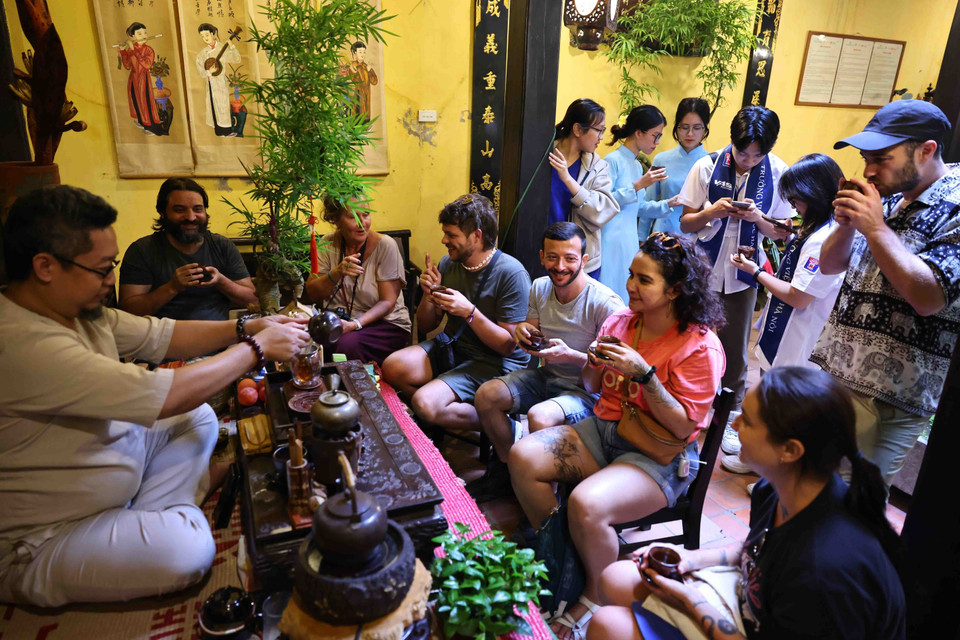 Các du khách nước ngoài thưởng thức trà tại Ngôi nhà di sản. (Ảnh: Minh Đức/ TTXVN)