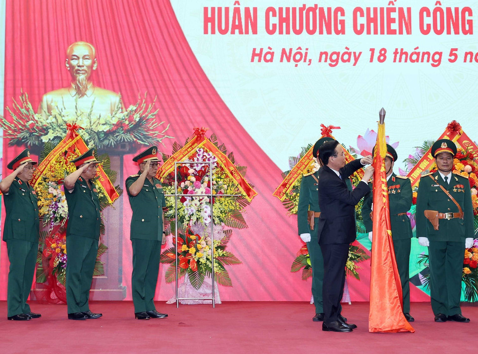 Chủ tịch nước Võ Văn Thưởng gắn Huân chương Chiến công hạng Nhất lên lá cờ truyền thống của Tổng Cục II, Bộ Quốc phòng. (Ảnh: Thống Nhất/TTXVN)