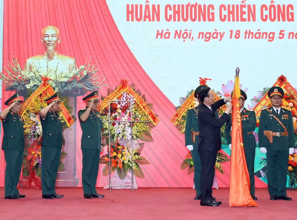 Chủ tịch nước Võ Văn Thưởng gắn Huân chương Chiến công hạng Nhất lên lá cờ truyền thống của Tổng Cục II, Bộ Quốc phòng. (Ảnh: Thống Nhất/TTXVN)