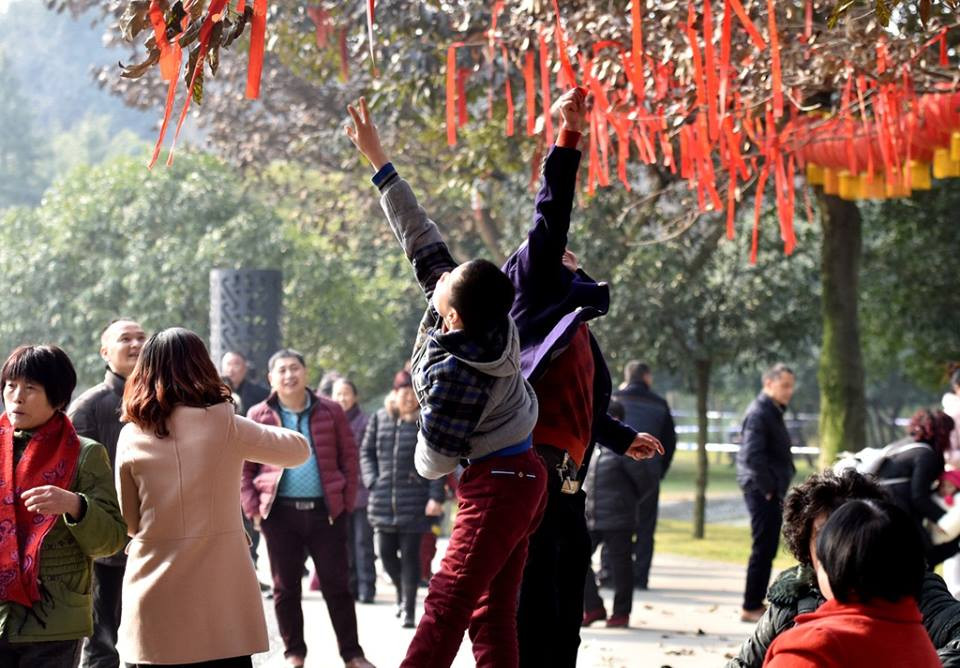 Người dân ở Đức Dương, một thành phố ở tỉnh Tứ Xuyên, đang kéo những dải lụa được buộc vào tán cây với hy vọng những điều ước của họ sẽ trở thành hiện thực và họ sẽ nhận được nhiều may mắn. (Nguồn: CCTV)