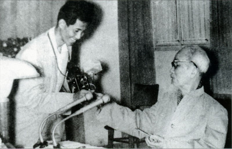 Chủ tịch Hồ Chí Minh tặng thuốc lá thơm cho nhà báo Lâm Hồng Long - tác giả của bức ảnh nổi tiếng Bác bắt nhịp Bài ca Kết đoàn. (Ảnh: Tư liệu TTXVN)