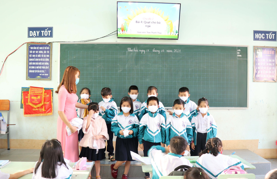 Giáo viên trường Tiểu học Nguyễn Lương Bằng hướng dẫn học sinh cách đeo khẩu trang, rửa tay khử khuẩn. (Ảnh: Hồng Điệp/TTXVN)