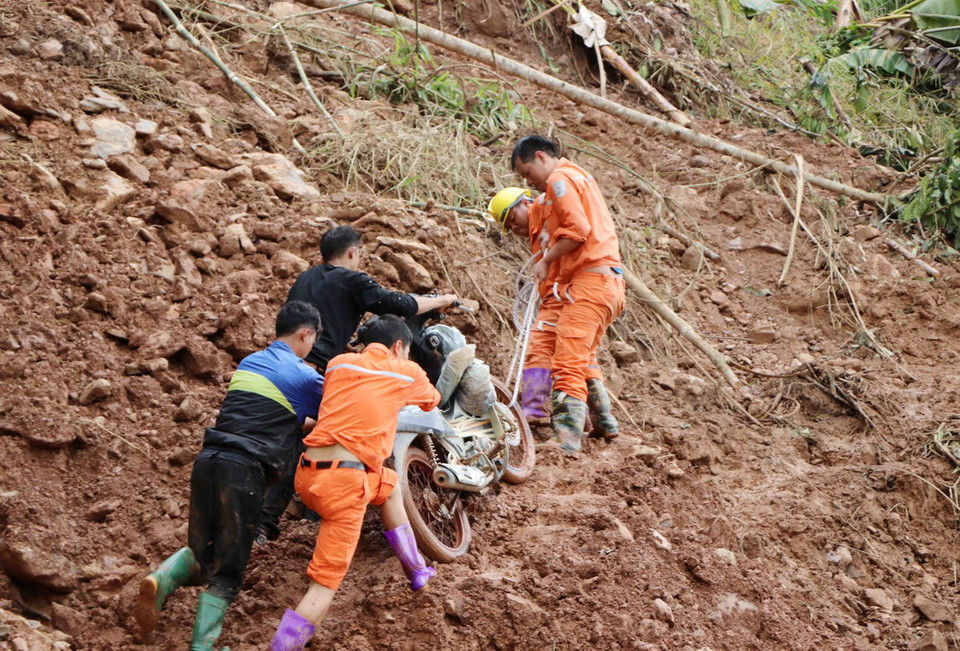 Trên đường đi khắc phục sự cố, cán bộ nhân viên kỹ thuật của công ty điện Nậm Nhùn (Mường Tè) giúp dân đưa phương tiện qua đoạn đường bị sạt trên quốc lộ 4H tại bản Ma Ký xã Mù Cả, huyện Mường Tè. (Ảnh: Quý Trung/TTXVN)