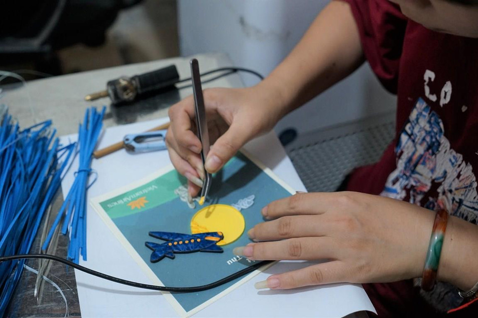 Các bạn khuyết tật chăm chú ghép dán từng chi tiết nhỏ lên thiệp. (Ảnh: Minh Tuấn/Vietnam+)