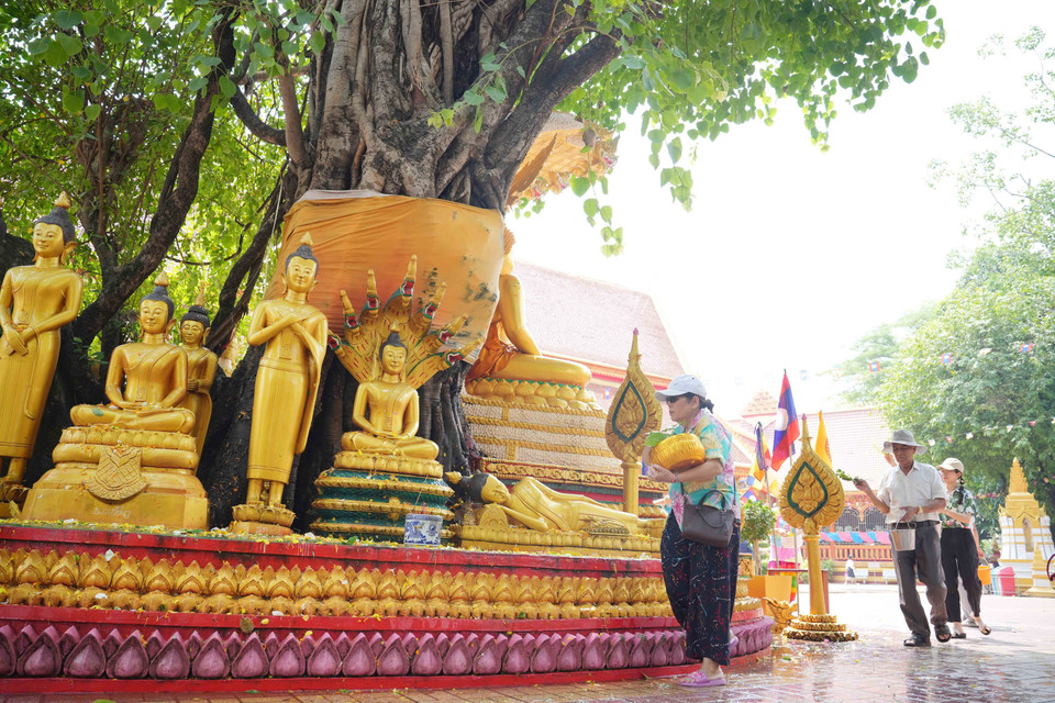 Người dân cùng nhau thực hiện nghi lễ tắm Phật phía ngoài sân chùa Simueang ở thủ đô Vientiane. (Ảnh: Đỗ Bá Thành/TTXVN)