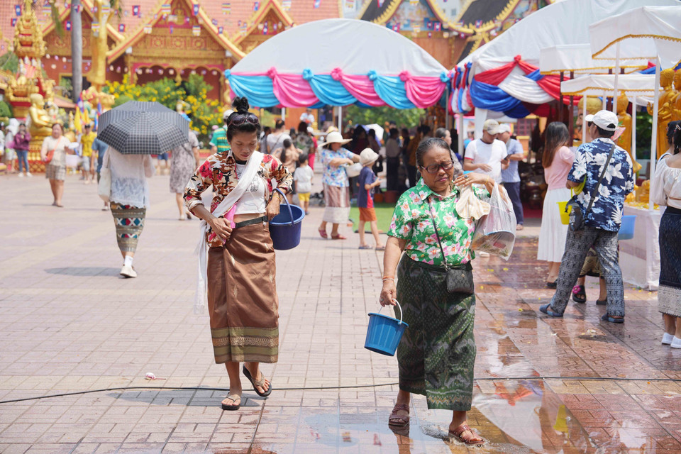 Người dân Lào tới chùa để thực hiện nghi lễ tắm Phật vào dịp Năm mới.(Ảnh: Đỗ Bá Thành/TTXVN)