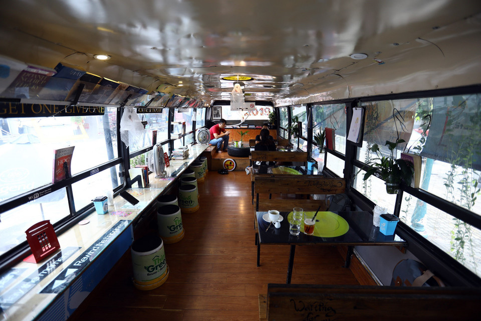 Bên trong chiếc xe buýt, toàn bộ ghế được thay thế bằng những chiếc bàn, ghế gỗ tận dụng từ lốp ôtô hỏng và thùng sơn bỏ đi. (Ảnh: Huy Hùng/TTXVN)
