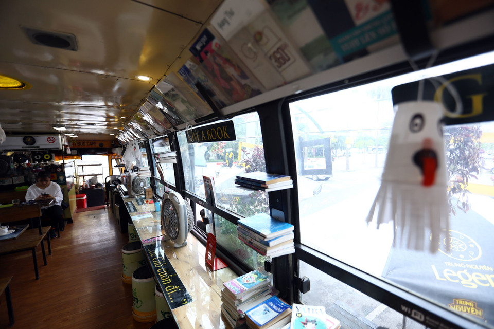 Bên trong chiếc xe buýt, toàn bộ ghế được thay thế bằng những chiếc bàn, ghế gỗ tận dụng từ lốp ôtô hỏng và thùng sơn bỏ đi.(Ảnh: Huy Hùng/TTXVN)